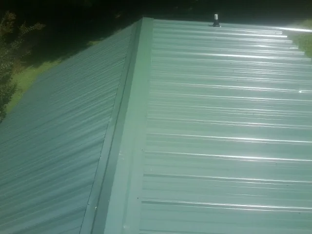 New green metal panels meeting at the ridge of a roof — Flat Roof Repair work by our crew in West Middletown