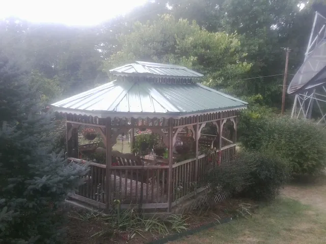 Green metal roof on a backyard gazebo surrounded by garden beds in West Middletown