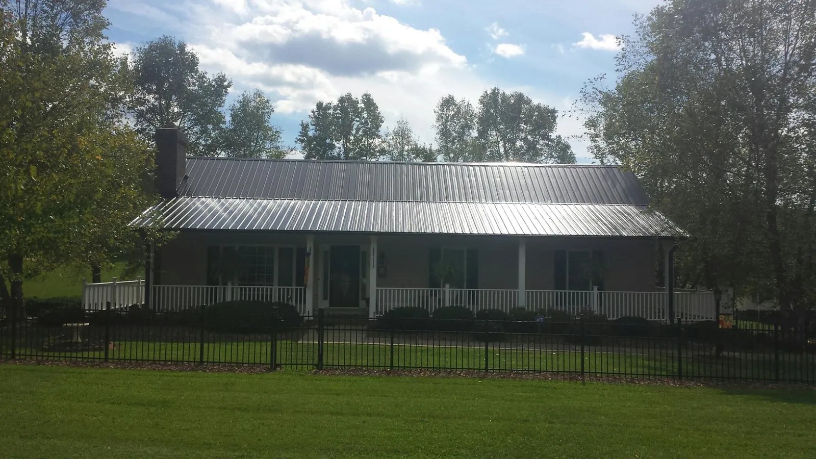 Gray metal roof on a brick ranch with a full width front porch — Gutter Guard Installation work by our crew in West Middletown