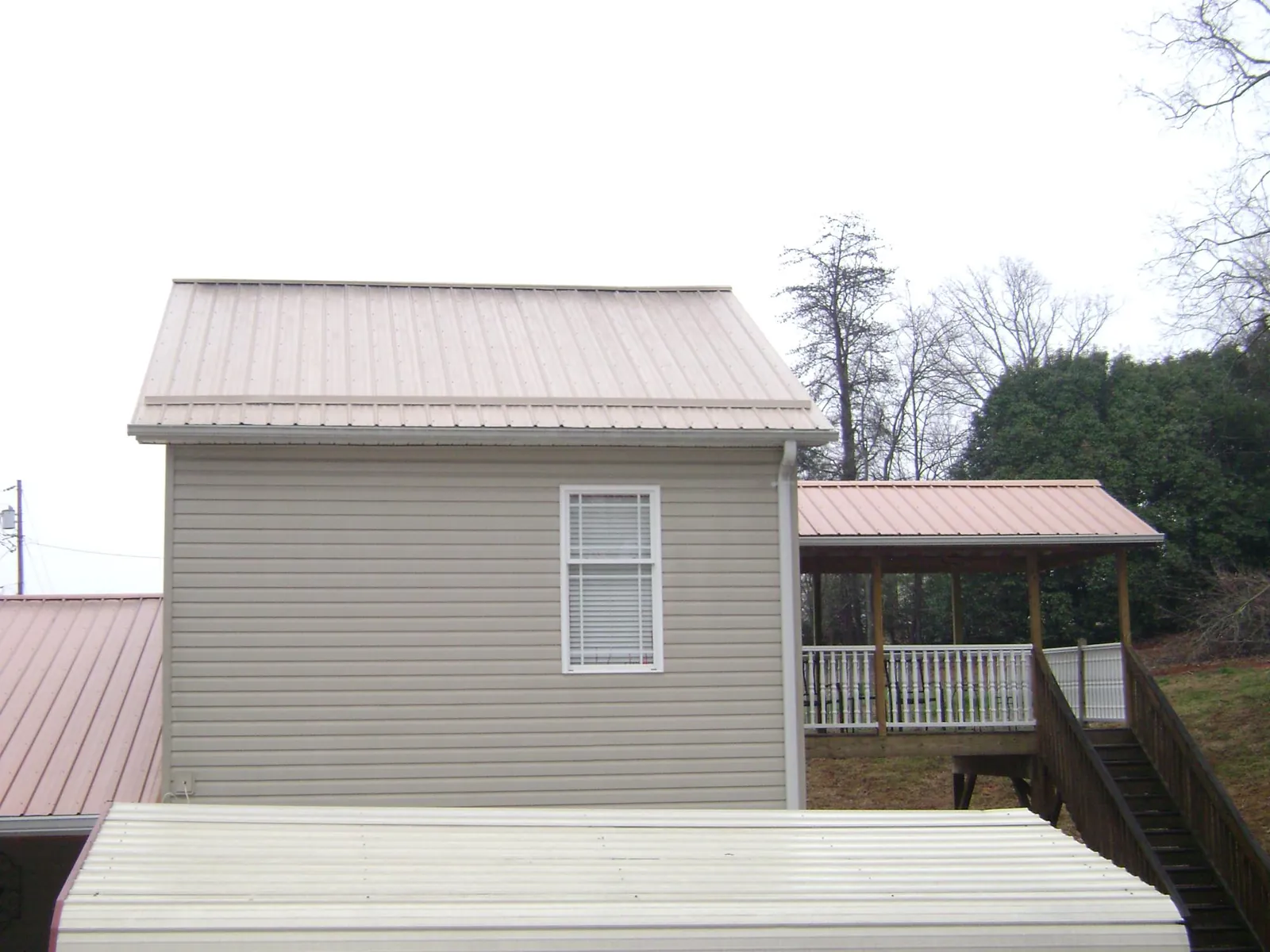 Tan metal roofs on a two story addition and attached porch, from a Roof Replacement job in West Middletown