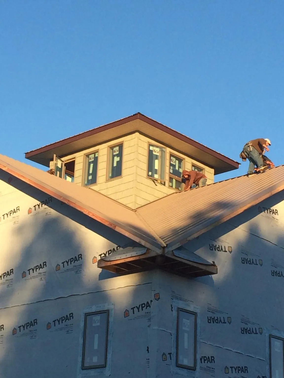 Roofers working around a rooftop cupola on a new metal roof at sunset — Roof Waterproofing in West Middletown by Roofing Brothers